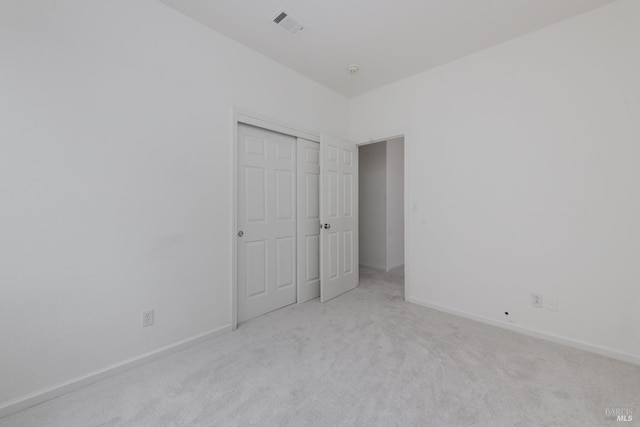 unfurnished bedroom featuring carpet, visible vents, a closet, and baseboards