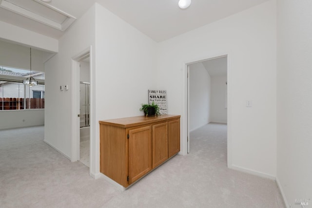 hallway featuring light carpet and baseboards