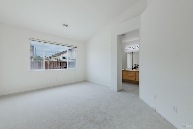 unfurnished bedroom with light carpet, visible vents, baseboards, and lofted ceiling