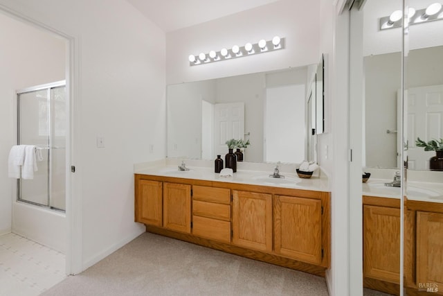 full bath featuring double vanity, bath / shower combo with glass door, and a sink