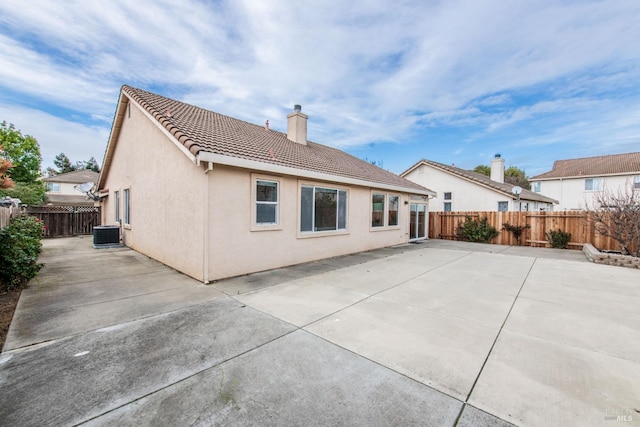 rear view of property with stucco siding, a tiled roof, central AC, and a patio