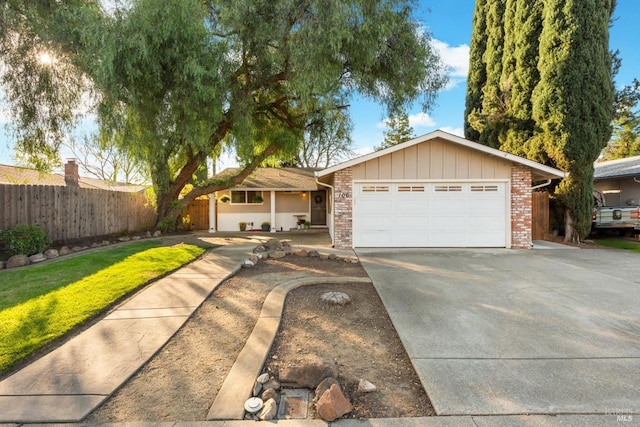 single story home with driveway, fence, board and batten siding, an attached garage, and brick siding