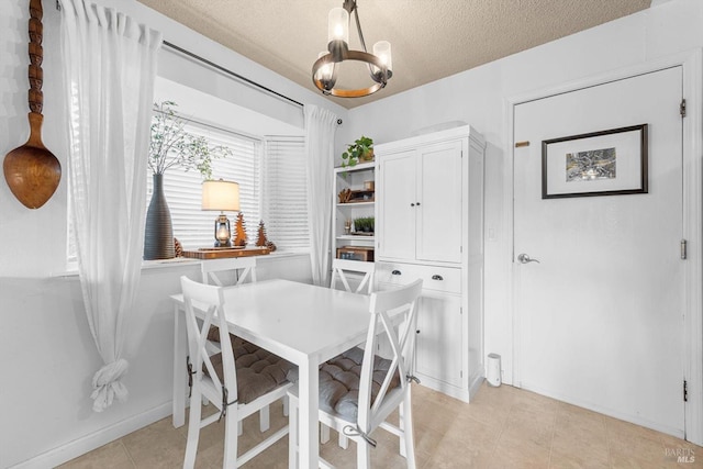 dining area with a chandelier, a textured ceiling, and baseboards