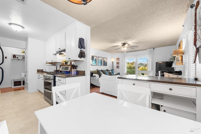 kitchen featuring white microwave, range with two ovens, ceiling fan, under cabinet range hood, and dark countertops