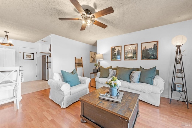 living room with light wood-type flooring, a textured ceiling, and a ceiling fan