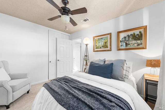 carpeted bedroom featuring ceiling fan, baseboards, visible vents, and a textured ceiling