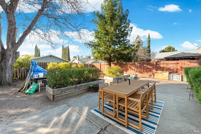 view of patio featuring outdoor dining area, a fenced backyard, and a garden