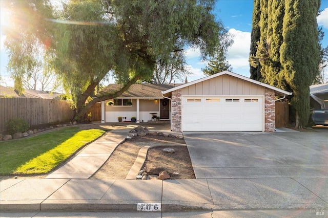 ranch-style home with fence, concrete driveway, a front lawn, a garage, and brick siding