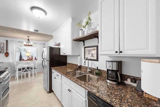 kitchen featuring visible vents, a sink, stainless steel appliances, dark stone counters, and white cabinets