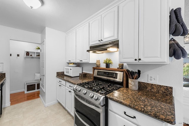 kitchen featuring under cabinet range hood, double oven range, white microwave, and white cabinetry