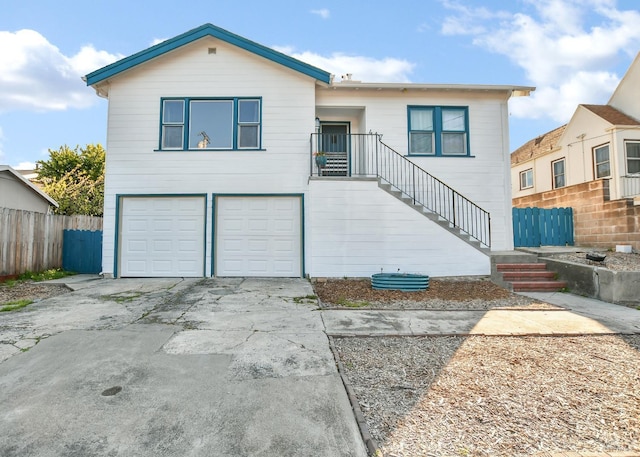 view of front facade featuring concrete driveway, stairway, an attached garage, and fence