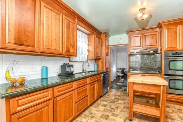 kitchen featuring a sink, under cabinet range hood, appliances with stainless steel finishes, tasteful backsplash, and brown cabinets