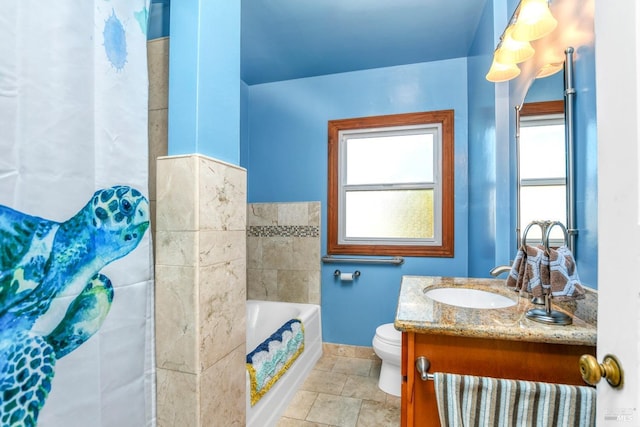 bathroom featuring vanity, a bath, baseboards, stone finish floor, and toilet