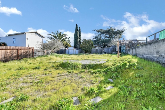 view of yard with an outdoor structure, a fenced backyard, and a shed