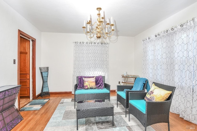 sitting room with baseboards, an inviting chandelier, and wood finished floors