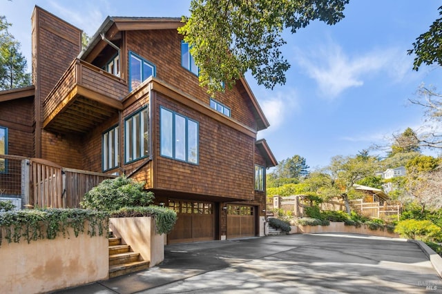 view of property exterior with a garage, driveway, and a balcony