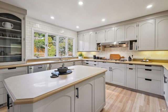 kitchen with ventilation hood, dishwashing machine, tasteful backsplash, and a sink