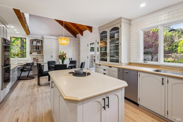 kitchen with a healthy amount of sunlight, appliances with stainless steel finishes, lofted ceiling with beams, and light wood-style floors