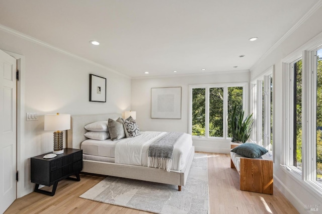 bedroom featuring multiple windows, ornamental molding, and light wood finished floors