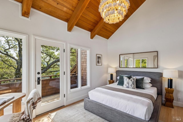 bedroom featuring multiple windows, wood finished floors, vaulted ceiling with beams, and access to outside