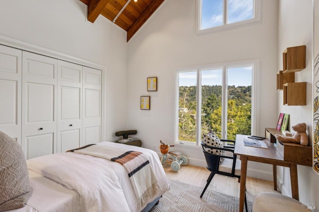 bedroom with wood finished floors, high vaulted ceiling, beam ceiling, a closet, and wooden ceiling