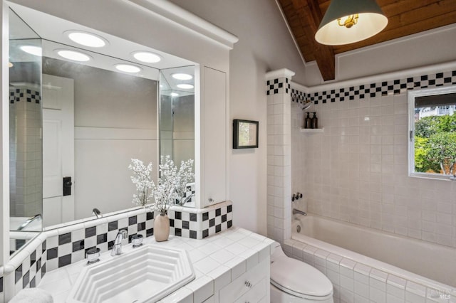 bathroom featuring vanity, toilet, and tiled shower / bath