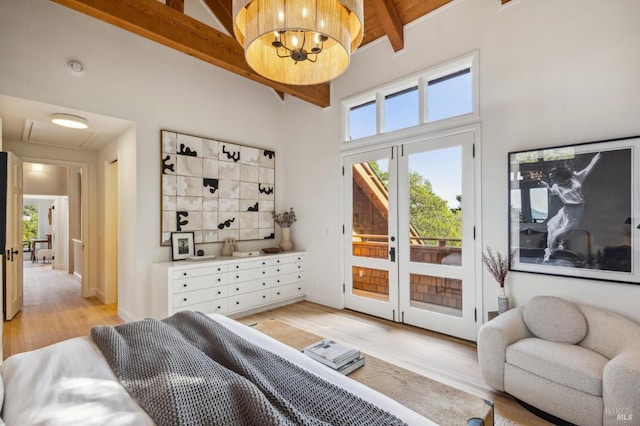 bedroom featuring light wood finished floors, beam ceiling, french doors, a high ceiling, and access to outside