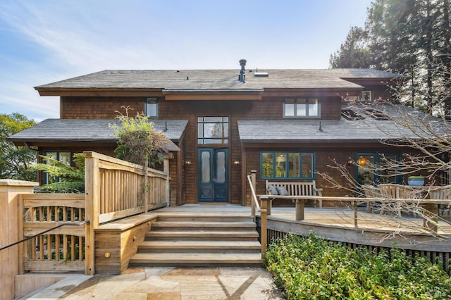 rear view of property with french doors, a deck, and roof with shingles