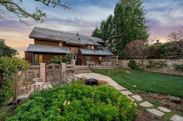 back of house featuring a deck, a patio, a yard, and fence