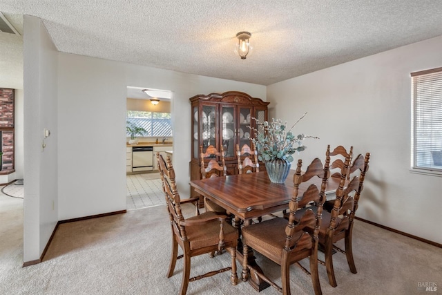 dining area with a textured ceiling, baseboards, and light carpet