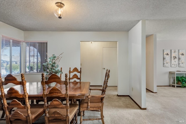 dining area featuring a textured ceiling, baseboards, and light carpet