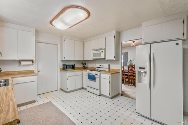 kitchen featuring light floors, white appliances, and white cabinets