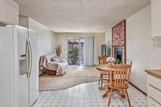 dining area featuring light colored carpet, light floors, a brick fireplace, and a textured ceiling