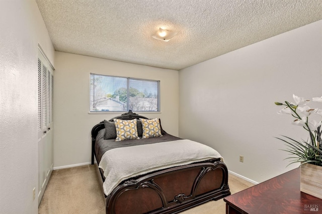 bedroom with a closet, baseboards, light colored carpet, and a textured ceiling