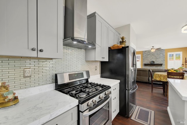 kitchen with tasteful backsplash, ceiling fan, wall chimney range hood, open floor plan, and stainless steel appliances