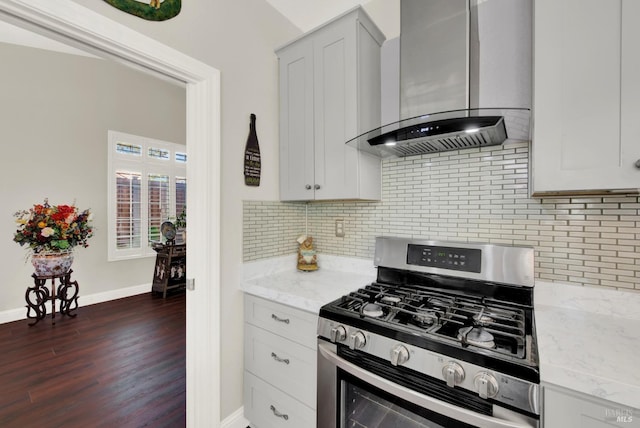 kitchen featuring light stone counters, stainless steel range with gas stovetop, decorative backsplash, dark wood-type flooring, and wall chimney range hood