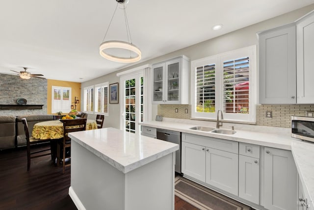 kitchen featuring a sink, open floor plan, a center island, stainless steel appliances, and decorative backsplash