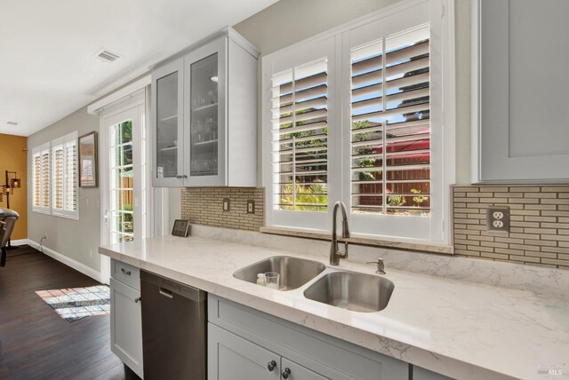 kitchen featuring light stone counters, visible vents, dark wood-style flooring, a sink, and stainless steel dishwasher