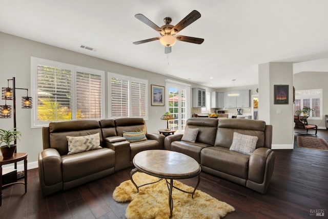 living room featuring a ceiling fan, dark wood-style floors, visible vents, and baseboards