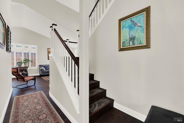 stairs featuring vaulted ceiling, baseboards, and wood finished floors