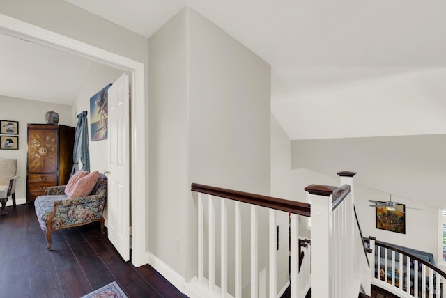 corridor with lofted ceiling, dark wood-style floors, an upstairs landing, and baseboards