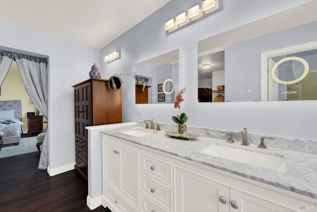 full bath with double vanity, connected bathroom, wood finished floors, and a sink