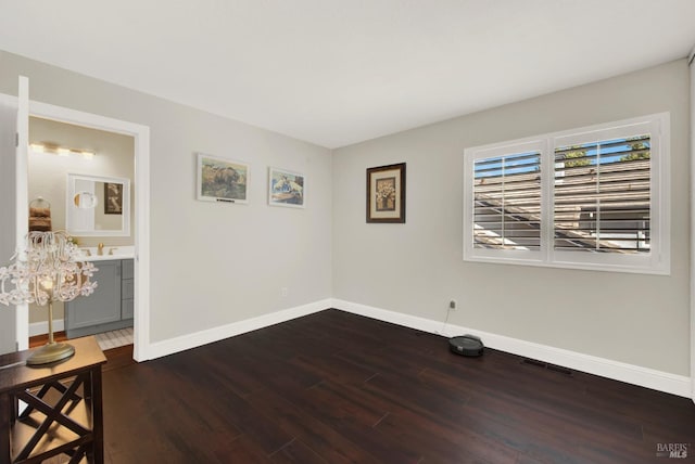 empty room with a sink, visible vents, baseboards, and dark wood-type flooring