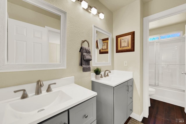 full bathroom with a sink, toilet, two vanities, and wood finished floors