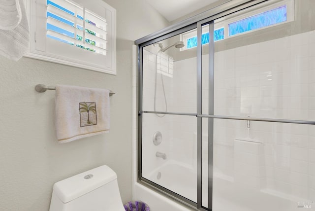 bathroom with shower / bath combination with glass door and toilet