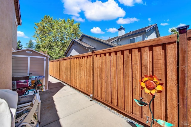 view of patio featuring a storage shed, a fenced backyard, and an outdoor structure