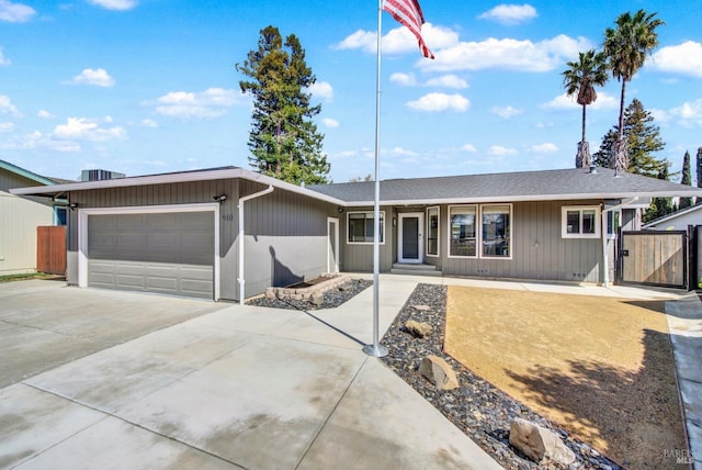 single story home with concrete driveway, a garage, and fence