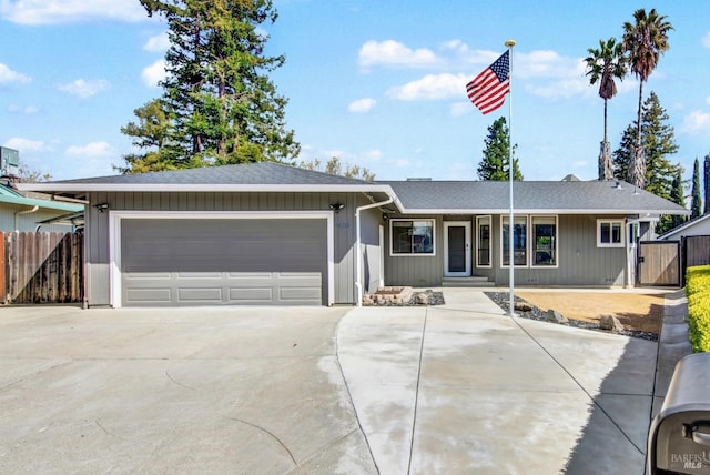 ranch-style house featuring an attached garage, concrete driveway, fence, and a gate