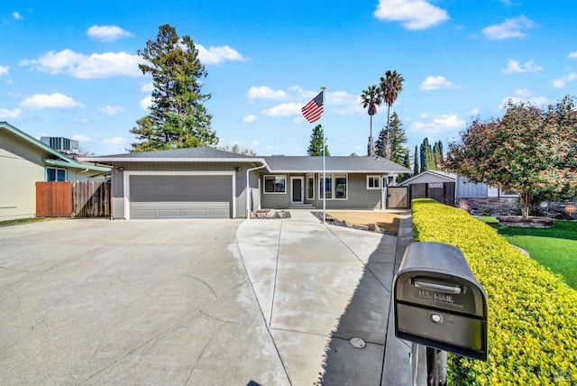 single story home with concrete driveway, central air condition unit, fence, and a garage