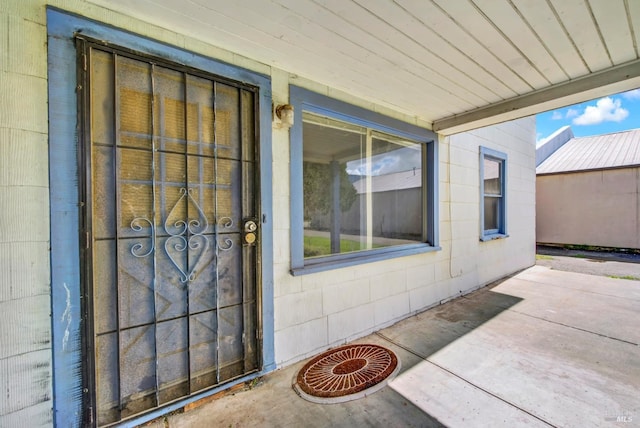 view of exterior entry featuring a patio and concrete block siding